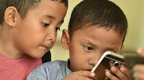 two kids engrossed in operating mobile