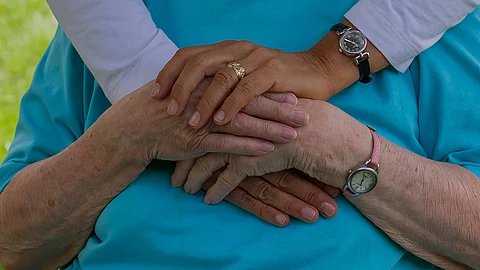 A woman gently holds her elderly person's hands, conveying love and support in a tender moment.