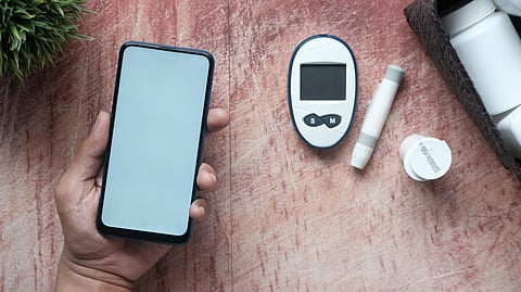 A blood glucose monitor and diabetes supplies arranged on a table, highlighting essential health management tools.