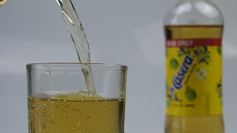 A glass is being filled with a yellow liquid.