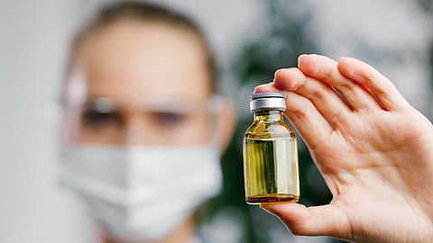Front view of female researcher with vaccine bottle