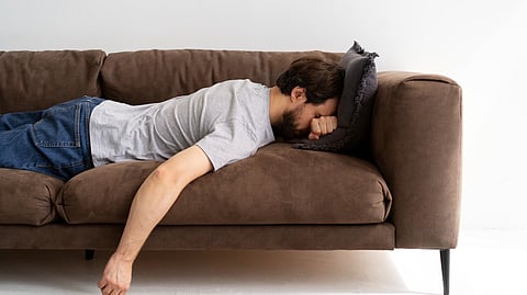 A man lying upside down on a couch.