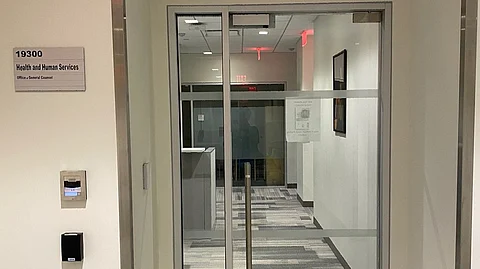 A clear glass door with a signboard of the HHS Office on the side.