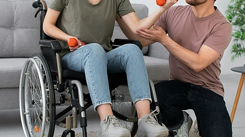 A woman on wheelchair doing exercise with dumbell