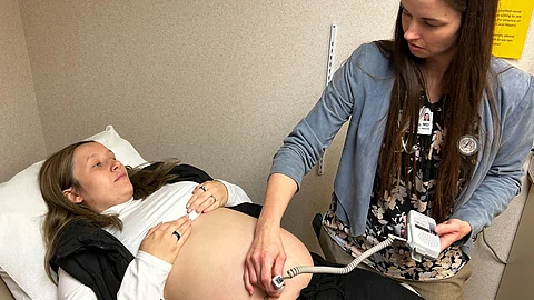 A female doctor is performing an ultrasound on a pregnant woman lying on a hospital bed.