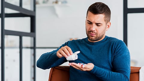 Man at home sitting on couch taking pills