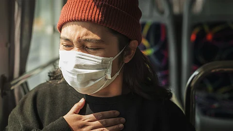 Sick woman in a mask having a difficulty in breathing.