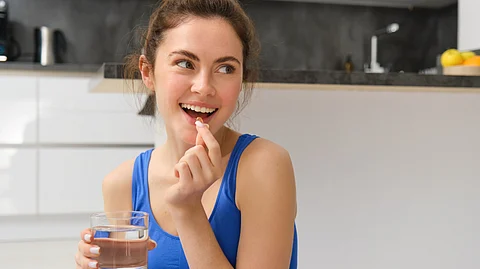 Close-up portrait of a woman taking vitamins, and a glass of water