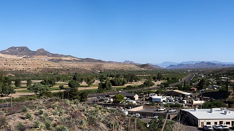 A scenic image showing mountains, trees, and blue sky.