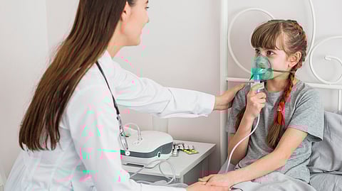 A young girl wearing an oxygen mask being examined by a female doctor.