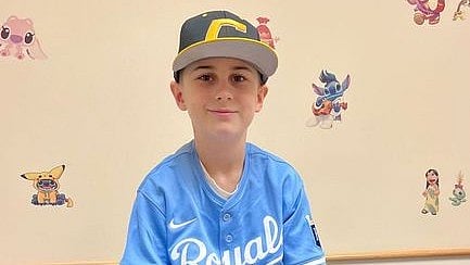 A boy named Colton George in blue t-shirt and a grey cap with yellow strip.