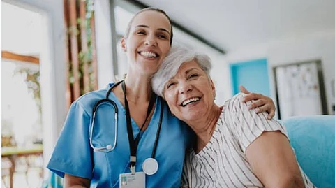 A lady doctor half hugging an elderly woman.