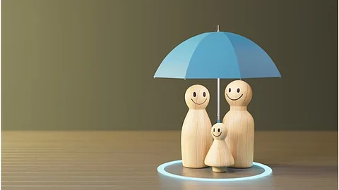 A wooden figurine depicting a family of three under a blue umbrella.