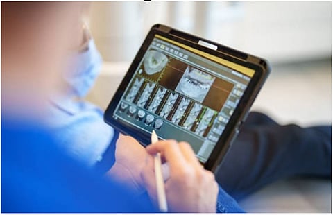 A dentist checking X-rays to measure root length during root canal treatment.