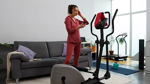 A woman is standing amid some training equipment in a living room.