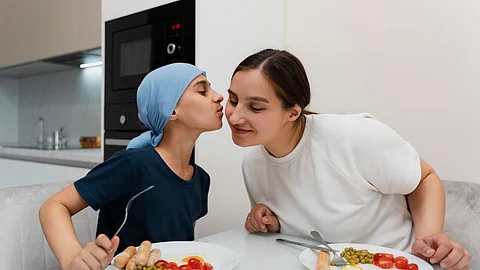 A child gives a kiss on the cheek of his mother and eats a healthy breakfast.