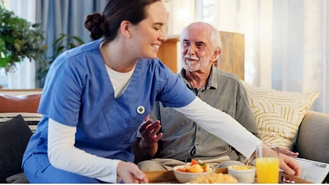 A nurse serving meals to an elderly man.
