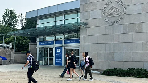 An image of a grey building with few people walking in front of them.
