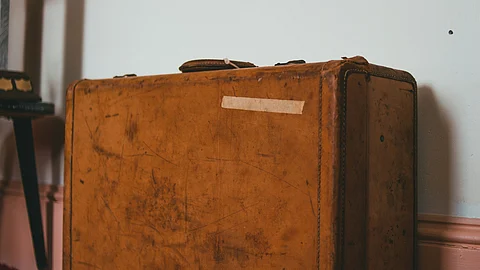 A brown suitcase resting on the floor, showcasing its textured surface and sturdy handle.