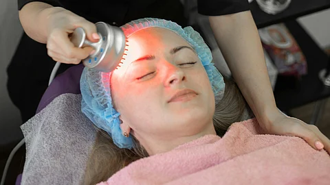 A person getting a massage with a red-light therapy device.