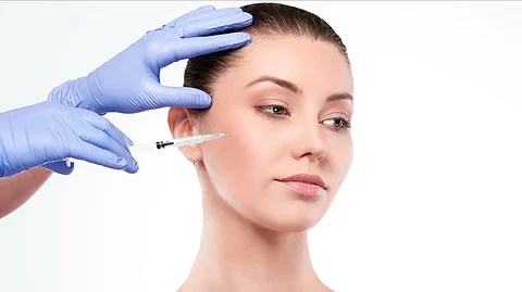 A woman getting an injection on her right side of her face.