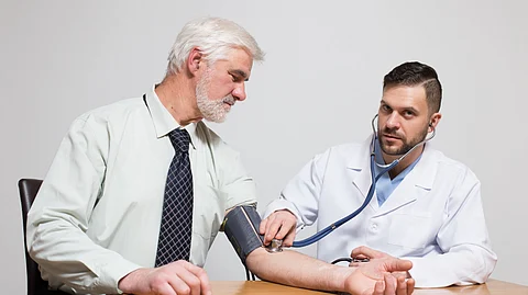 An elderly man is getting his blood pressure checked by a doctor.