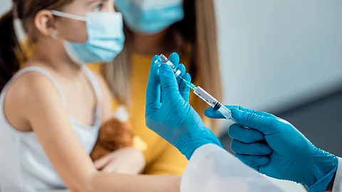 Closeup of a doctor preparing a syringe to give an injection to a young girl.
