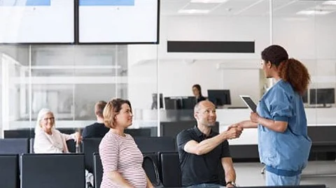 A healthcare professional talking to some patients in the waiting area.