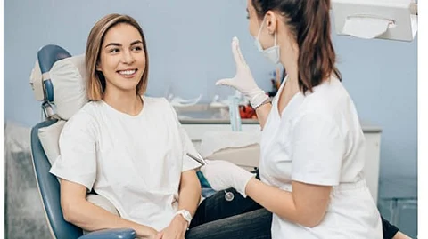 A woman on a dental chair smiling at a female dentist.