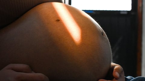 Close-up of a pregnant belly with a hand gently cradling it, highlighting the beauty of motherhood.