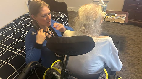 The image shows Stephanie Johnson checking her patient Ellen with a stethoscope.