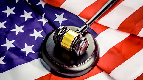 A gavel resting on a wooden block placed over a U.S. flag, symbolizing federal decisions and legal authority.