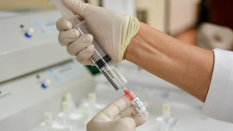 Image showing a scientist collecting some transparent liquid into a vial.
