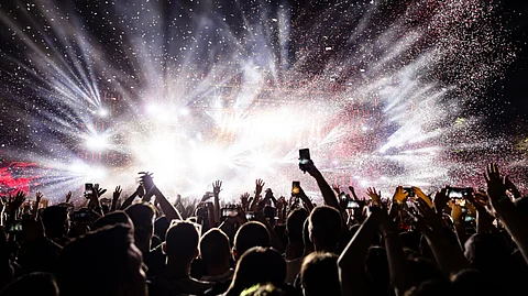 An excited audience is enjoying a music festival and recording the event.