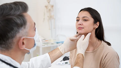 A doctor is checking the chin of a female patient during an examination.