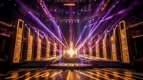 A brightly lit stage of an award show is illuminated by colorful lights, creating a vibrant atmosphere.