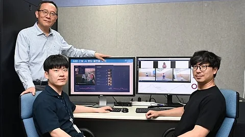 The image shows three male scientist pose in an office, in front of computer monitors.