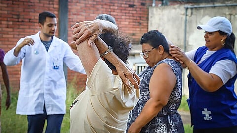 Physiotherapist with a white coat and an exercise instructor helping older women with their physical activity training.