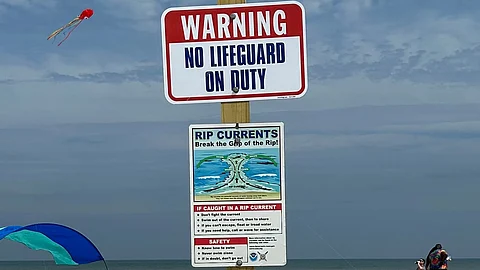The picture shows two warning boards, one with 'No Lifeguard on Duty' written on it.