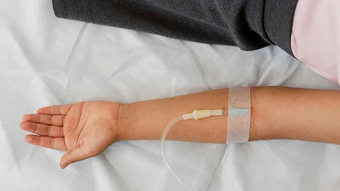 Patient on hospital bed with IV drip attached to his hand.