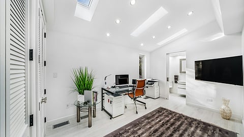 A well-organized clinic with a desk, a comfortable chair, and a television for video calls.