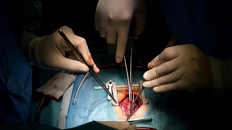 A surgeon in scrubs performing surgery on a patient on an operating table in a sterile environment.