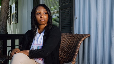 An image of Brianna outside her home sitting on a bamboo chair.