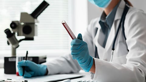 A female doctor working on vial samples wearing blue gloves and noting some points.