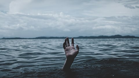The image shows a outstretched hand reaching above water, symbolizing drowning