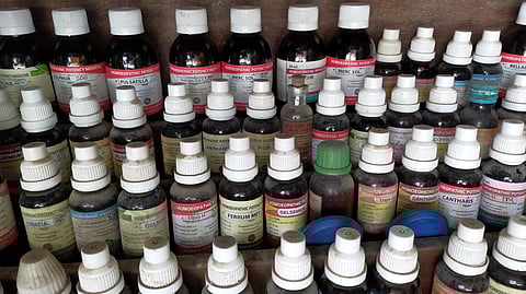 Numerous bottles of homeopathic medicine are arranged on a shelf.