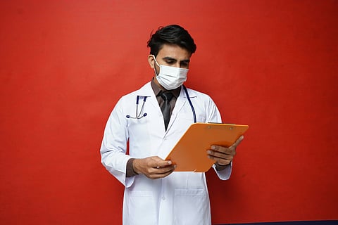 A medical professional reading a file in a red background.