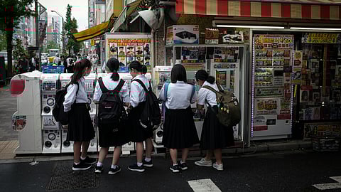 A group of school-going girls is standing outside a shop.