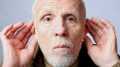 An old man is placing both his hands on his ears indicating hearing impairment.