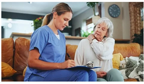 A nurse is writing some notes in a pad after talking to a senior lady.